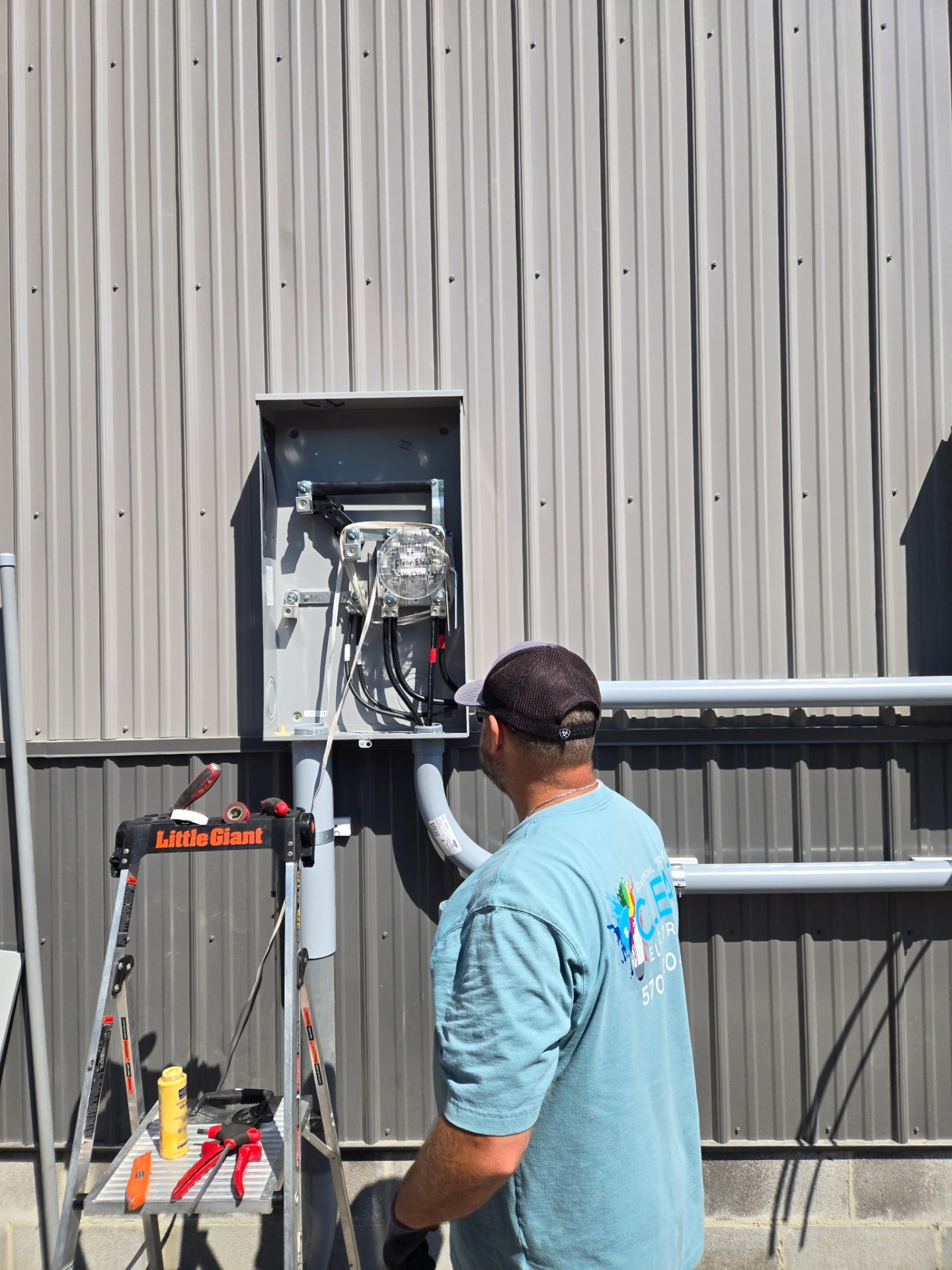 Clear Electric technician wiring an exterior meter disconnect on a metal commercial building