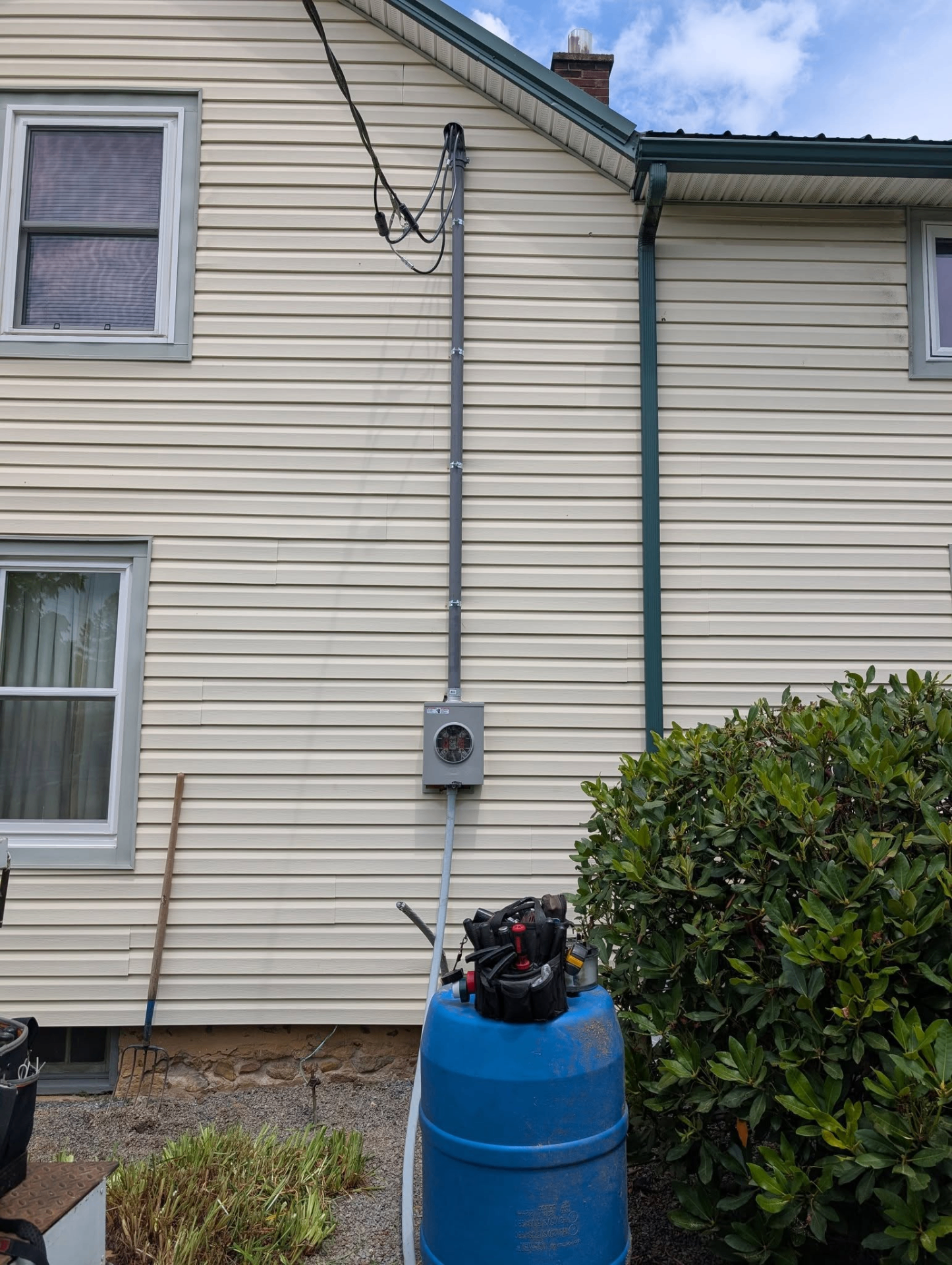 Exterior house wall with new meter socket and service riser installed from ground to roofline