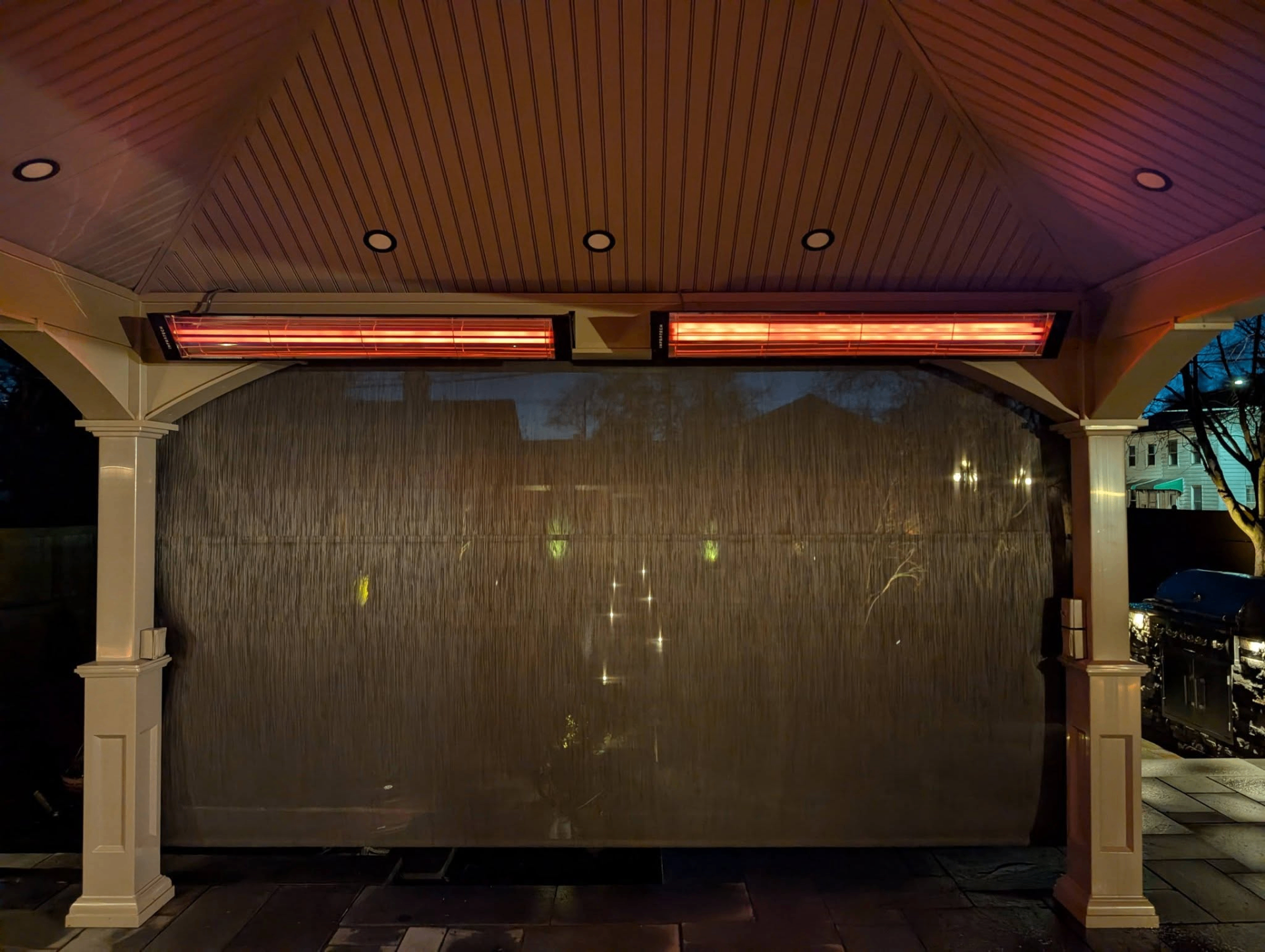Mounted electric patio heaters above a screened outdoor seating area
