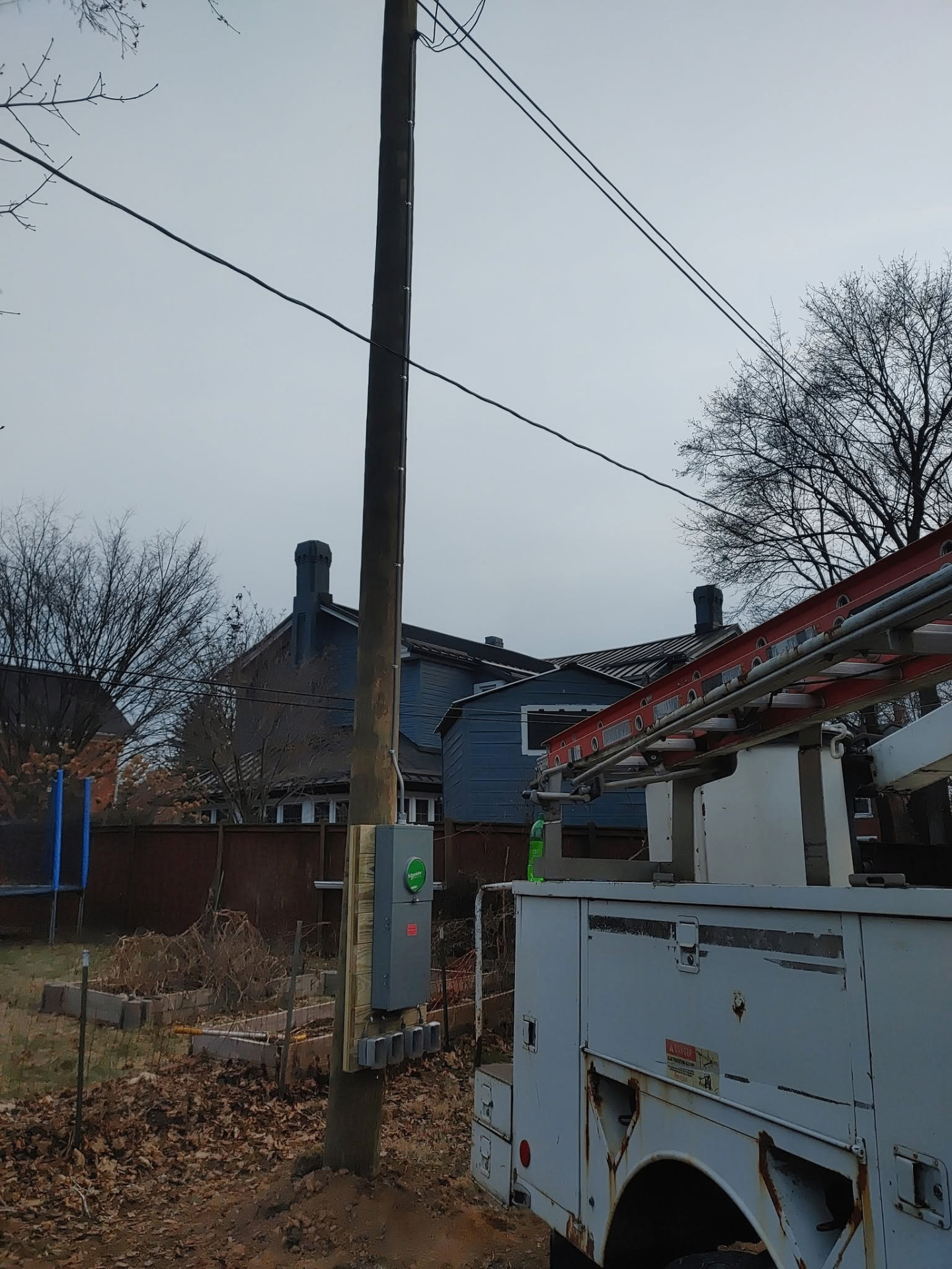 New utility service pole with mounted disconnect and meter base in a residential backyard